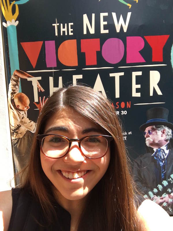 Miranda Cornell poses in front of a New Victory poster
