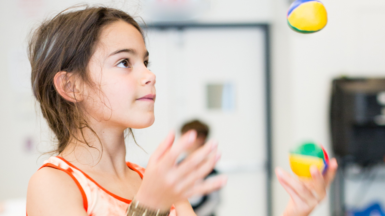 A young girl practices juggling