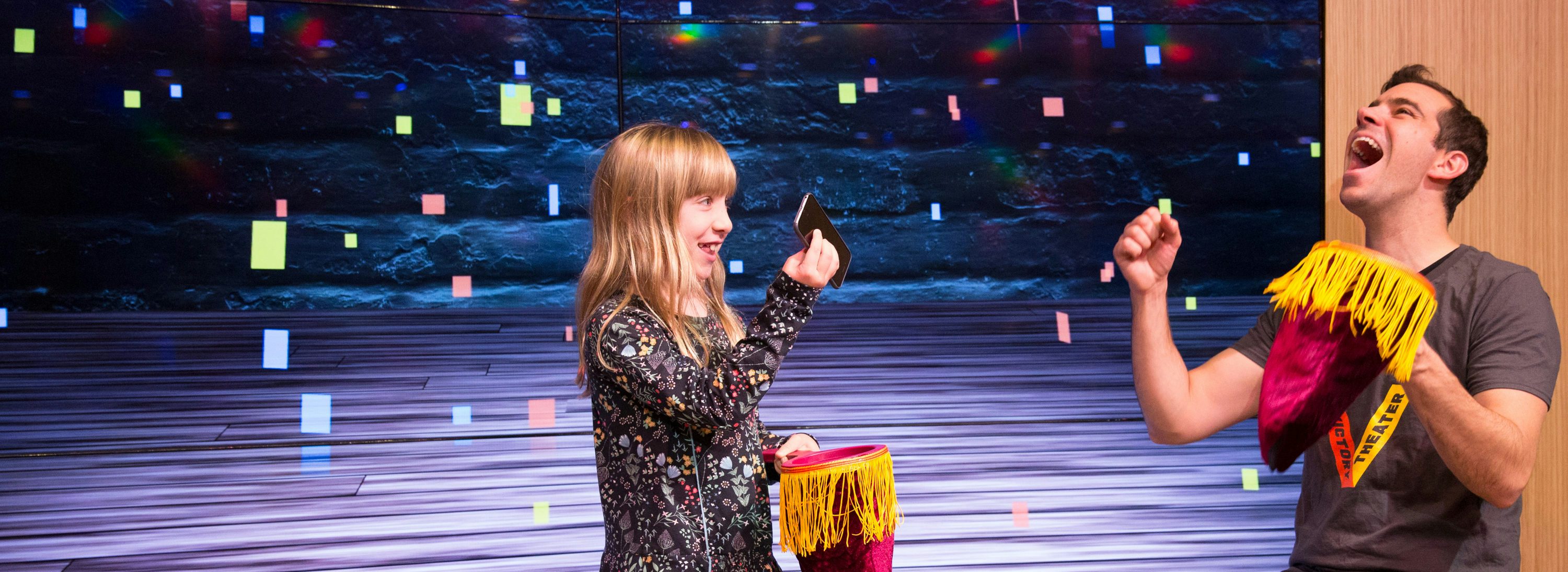 A young girl practices a magic trick with a New Victory Teaching Artist.