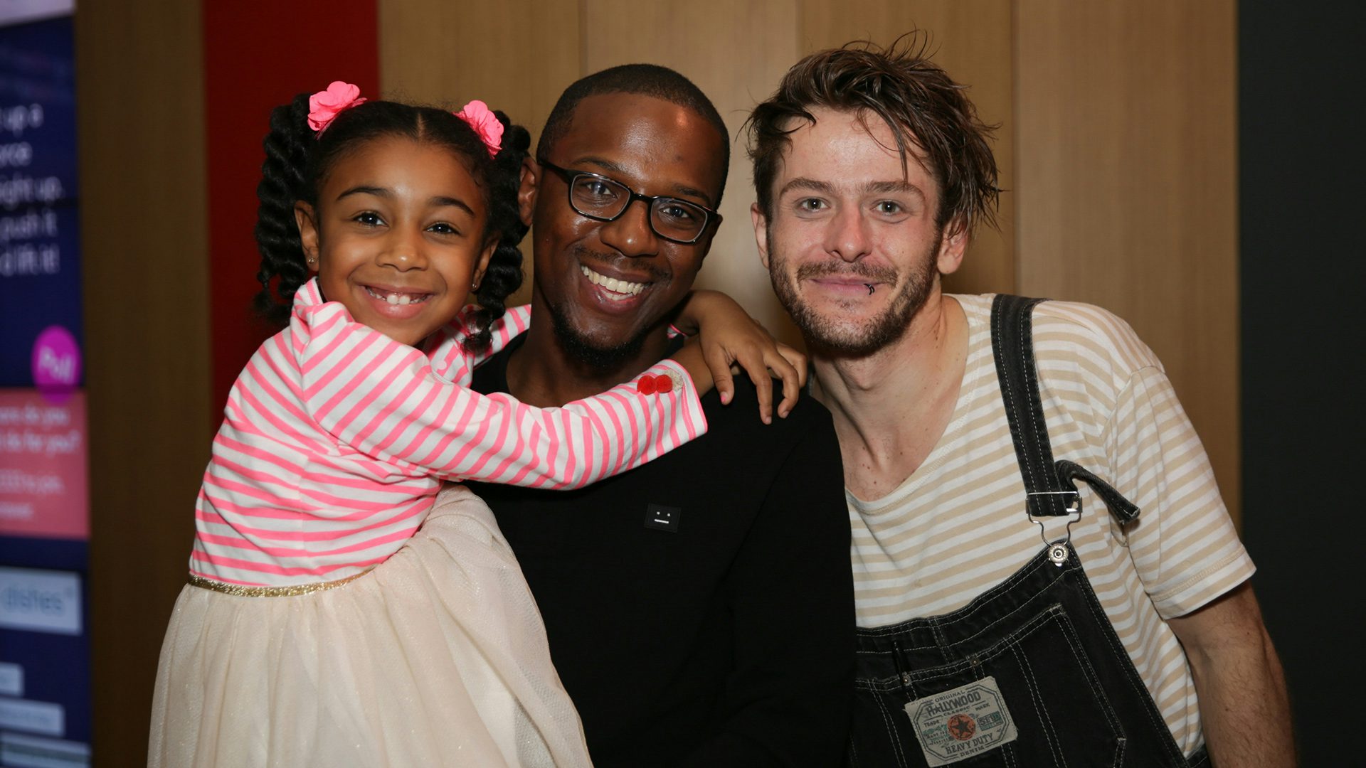 Smiling dad and daughter pose for a post-show photo with a cast member.