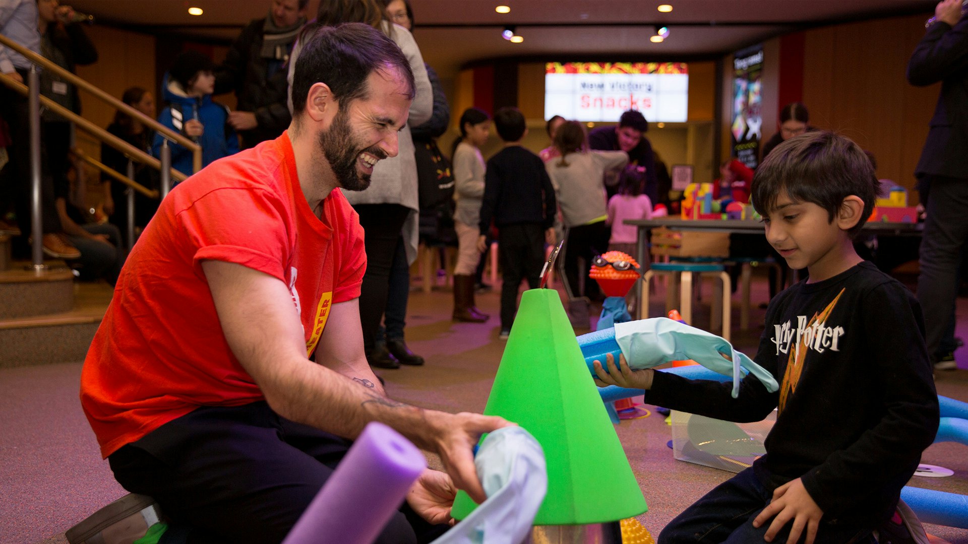 A smiling Teaching Artist leads a boy in a pre-show activity.