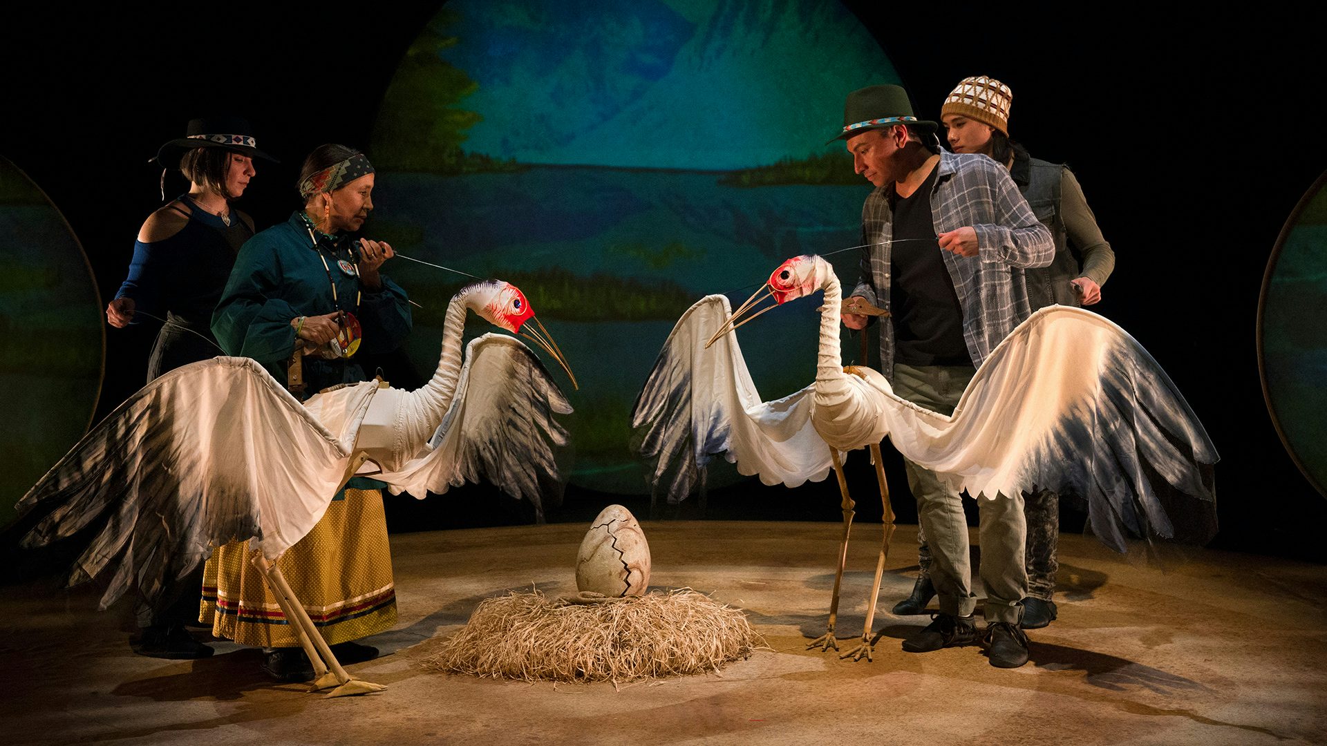Several cast members operate two large crane puppets in a scene from Ibex Puppetry's Ajijaak on Turtle Island.