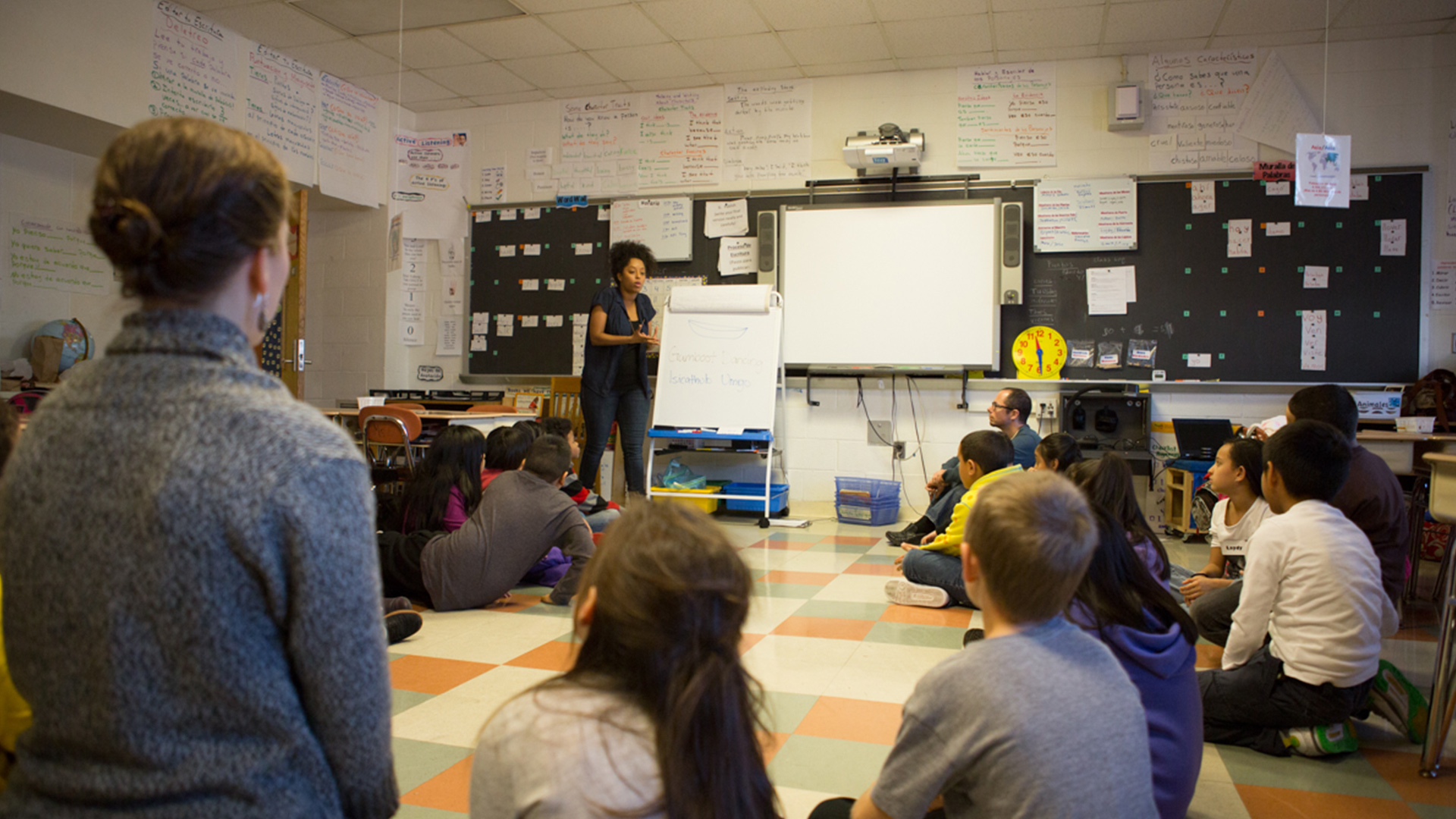 Inside a classroom, a Teaching Artists, instructs a group of kids