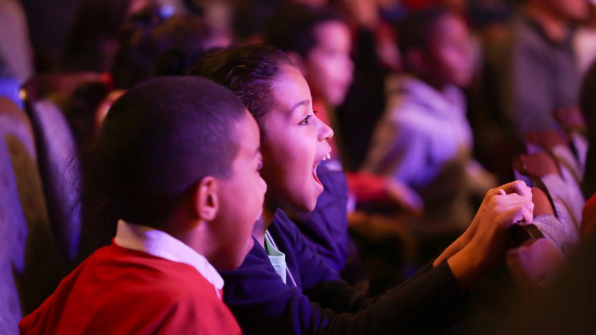 A young girl and boy react to a performance with open-jawed amazement.