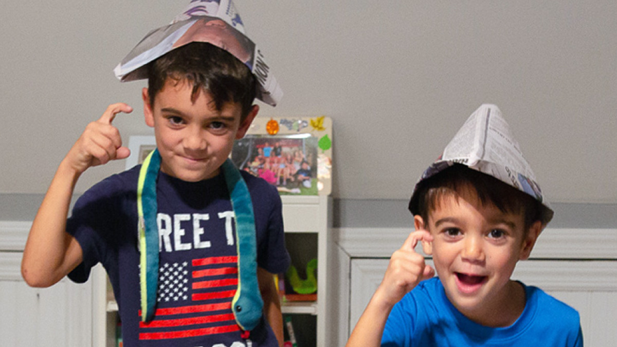 Two young boys wear newspaper hats and act like pirates to complete a mission in The Great New Victory Scavenger Hunt.