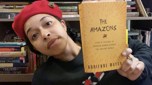 ChelseaDee Harrison holding a book titled The Amazons