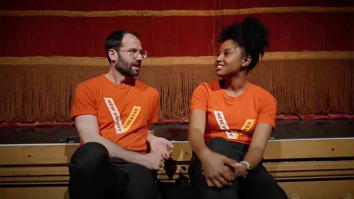 New Victory Teaching Artists Patrick Fererri and Melle Phillips sit in front of the New Victory stage.