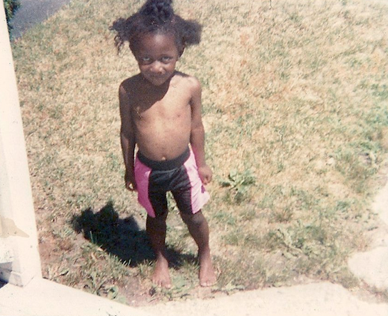 nicHi douglas, age 4, standing barefoot on a lawn wearing shorts and no top