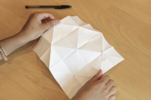 Unfolded fortune teller with many diagonal creases from folding