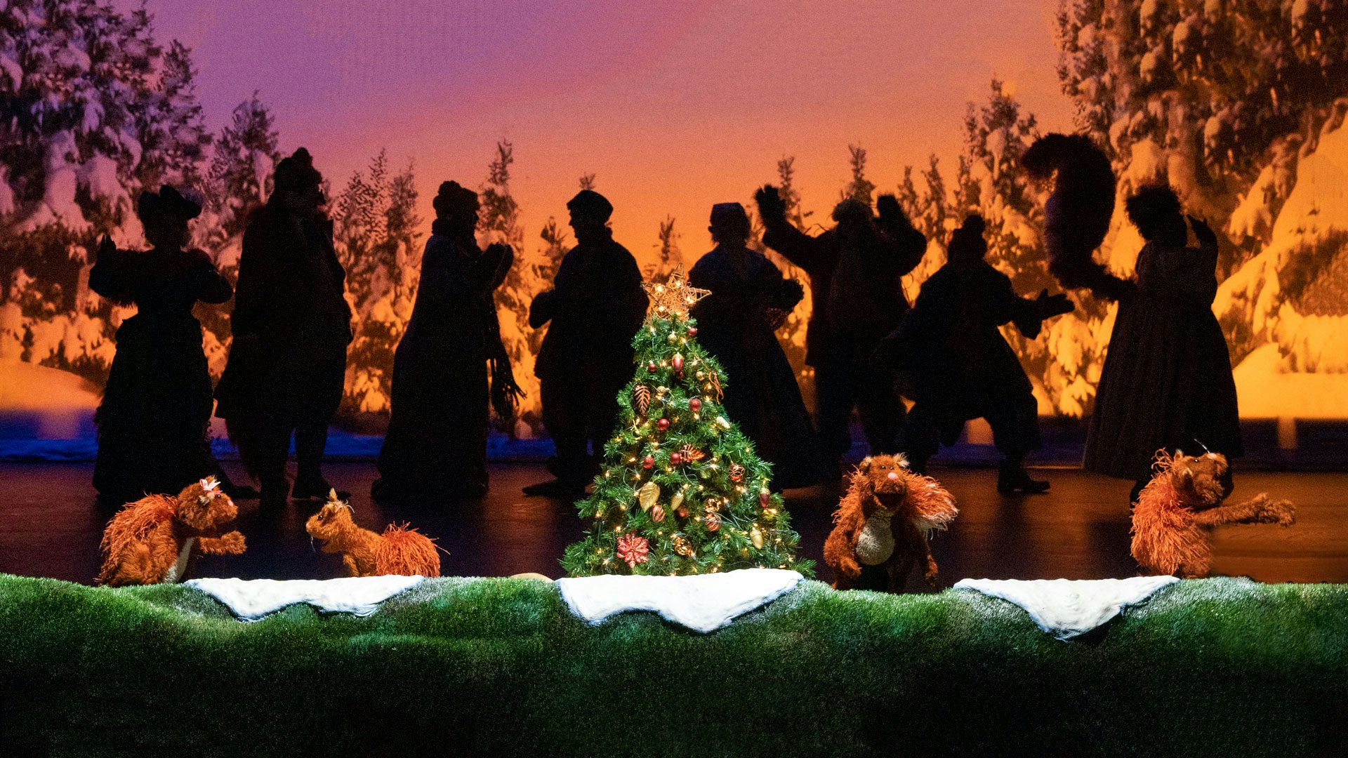 Squirrel puppets gather around a Christmas tree with the silhouetted cast of Jim Henson's Emmet Otter's Jug-Band Christmas. Photo: Richard Termine
