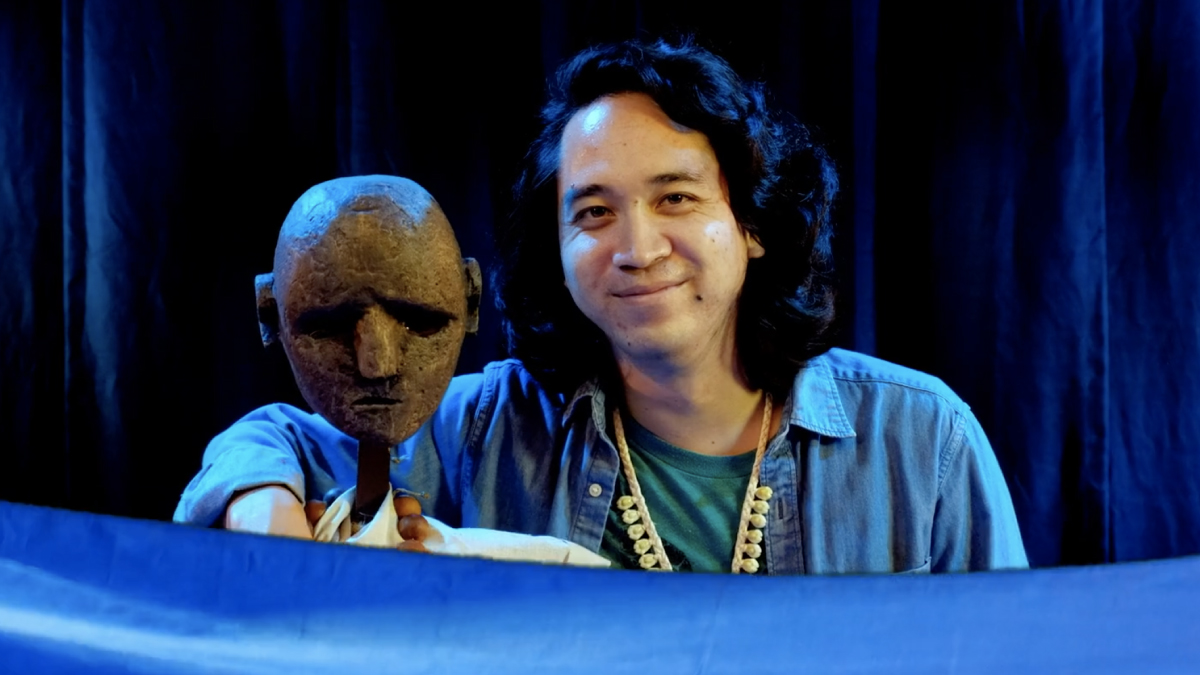 Actor Sean Choo poses next to a puppet head.