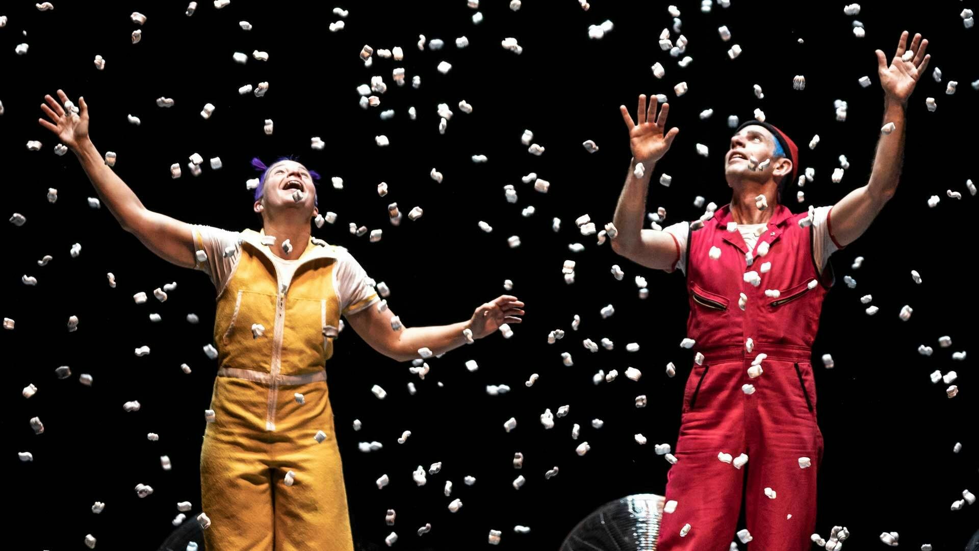 Acrobuffos surrounded by packing peanut confetti.