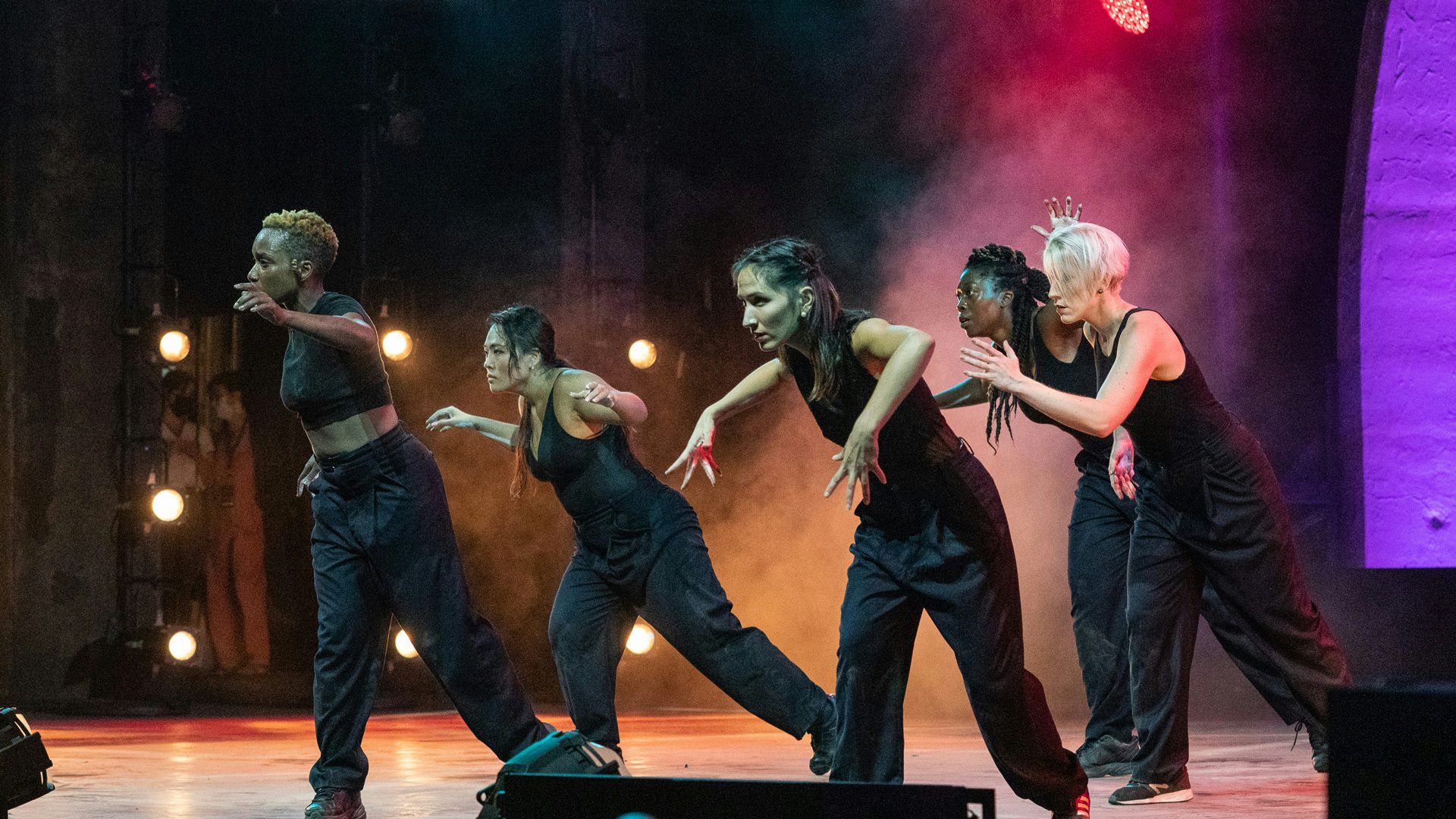 Five dancers from Passion Fruit Dance, mid popping and locking.