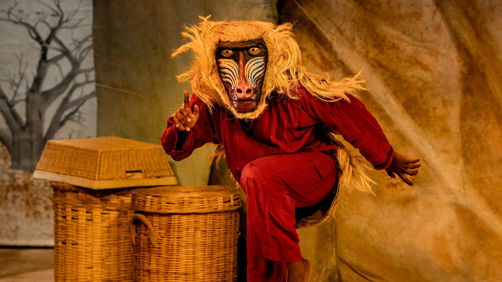 An actor wears a hand-painted mask of a monkey.