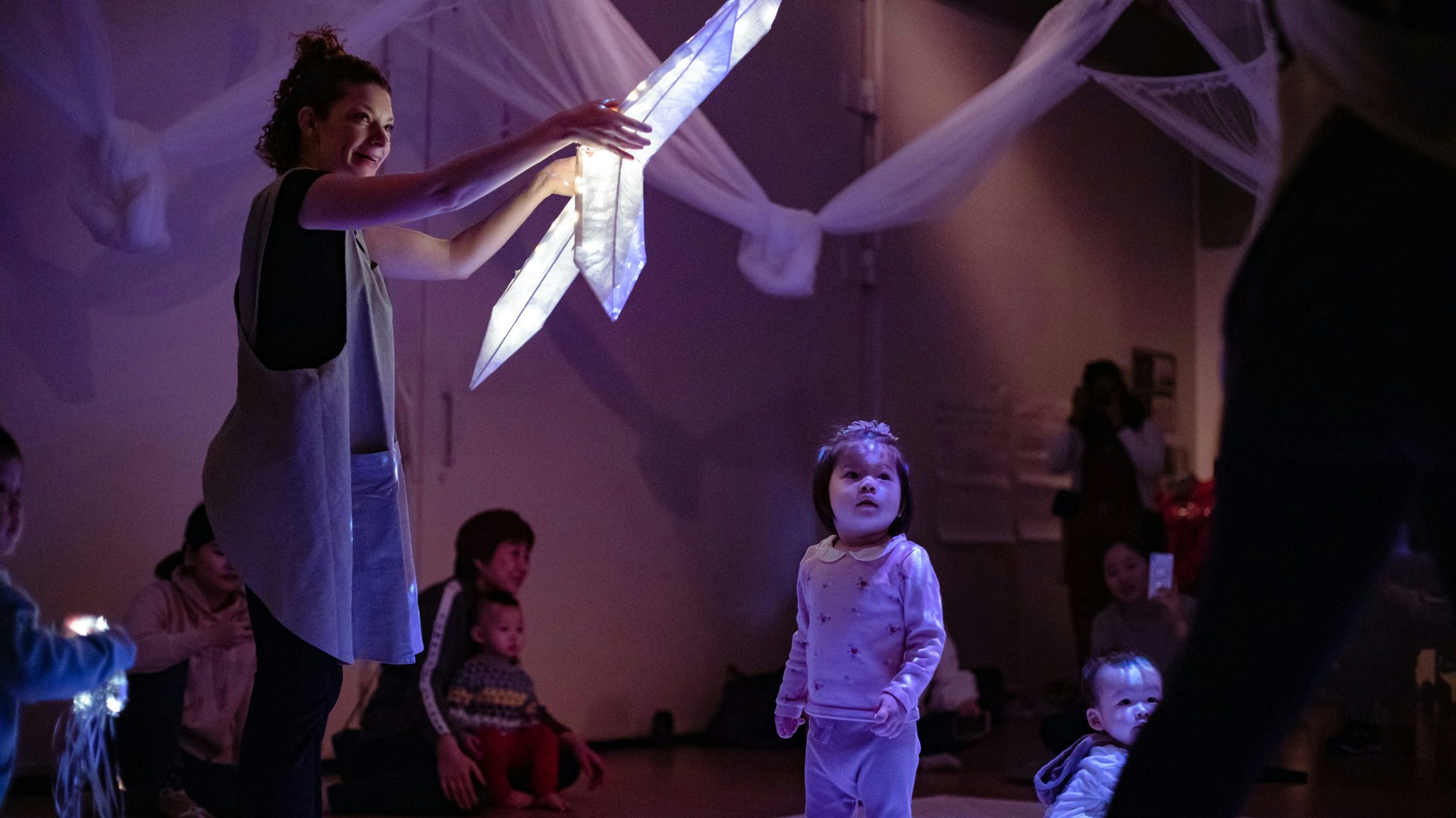 An actress holds a star-shaped paper lantern in her hands, while a child gazes up at it.