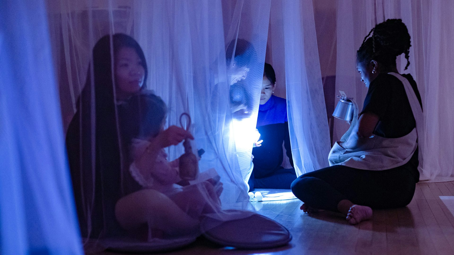 Families sit inside mesh-like tents, watching the performance of Shakespeare's Stars.