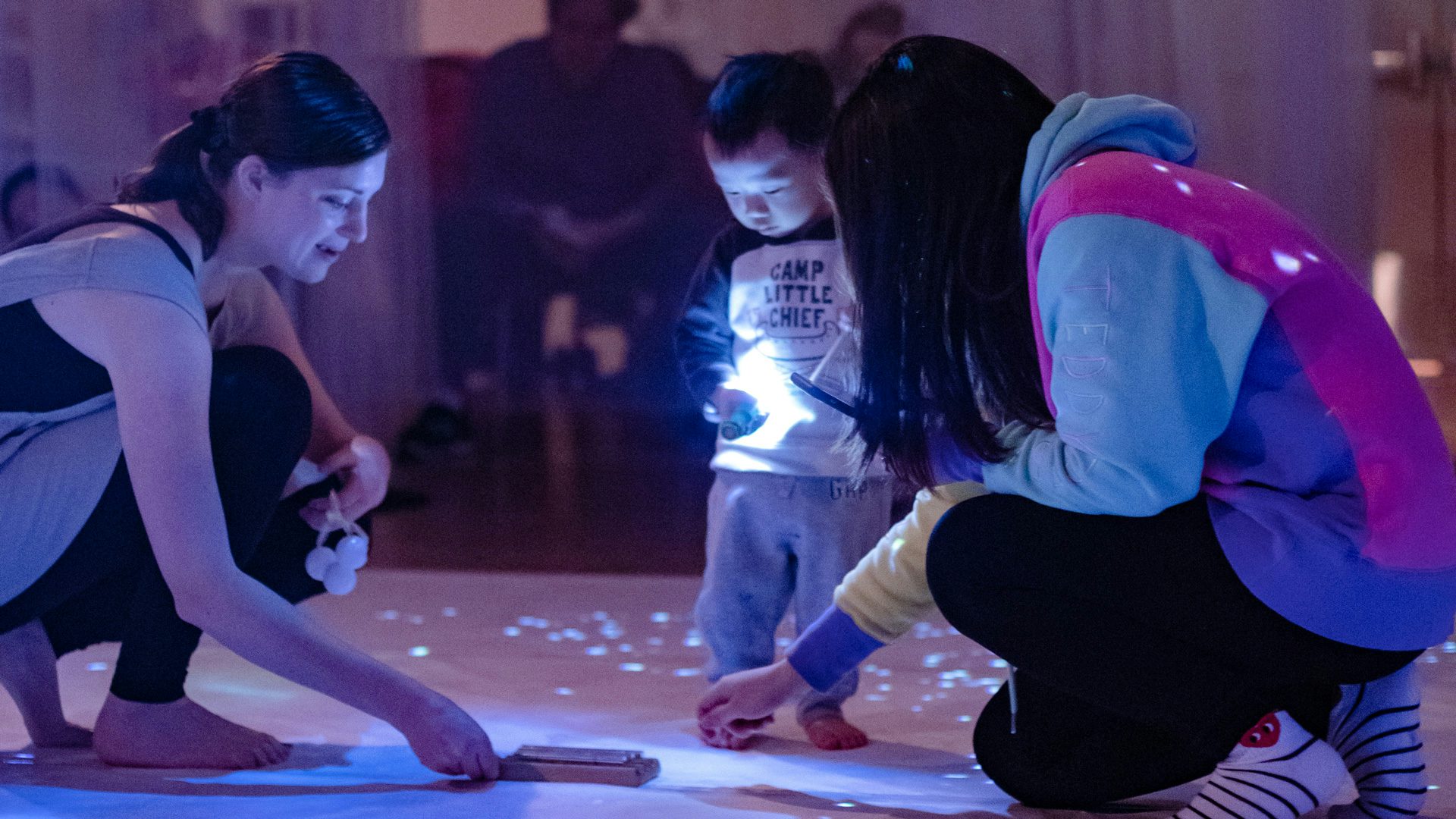 An actress offers a child and his mom an mini-harp to explore.