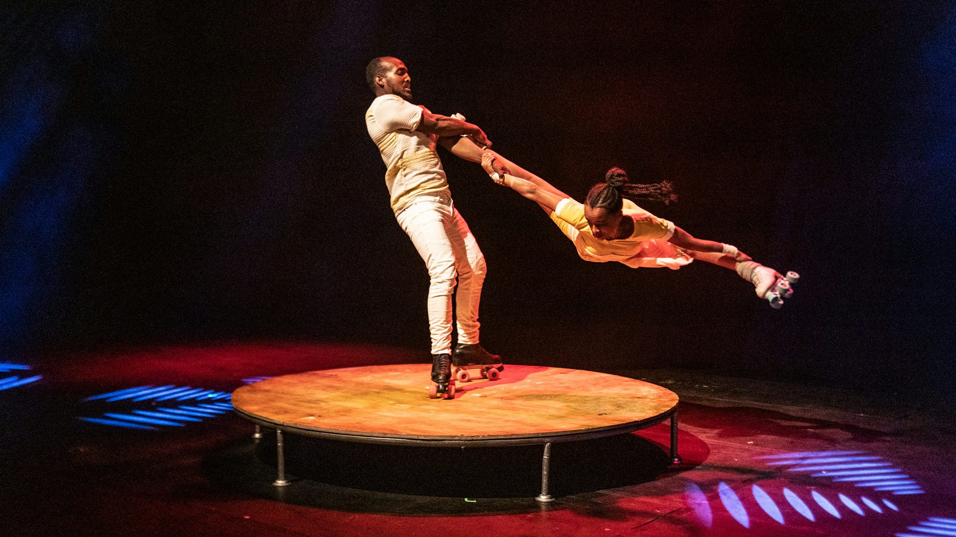 A man on roller skates suspends a woman in the air.