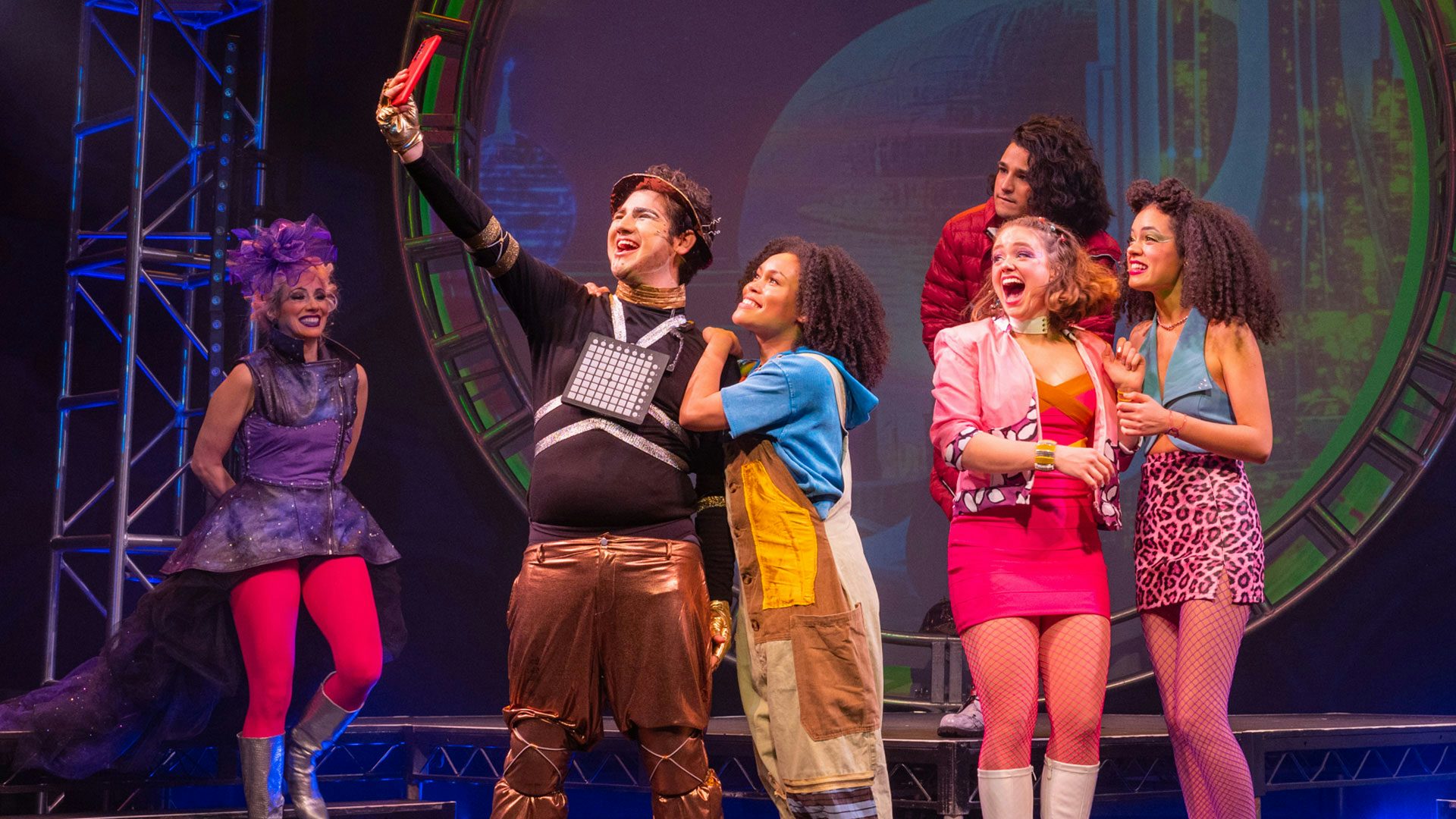 The cast of Hip Hop Cinderella on stage during a musical number taking a group selfie