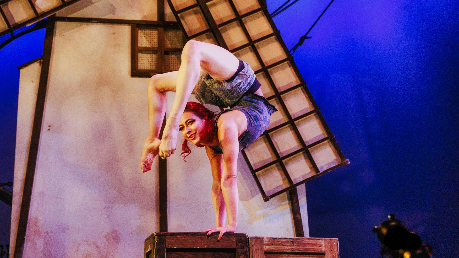 An inverted woman balancing on her hands with her feet touching her head.