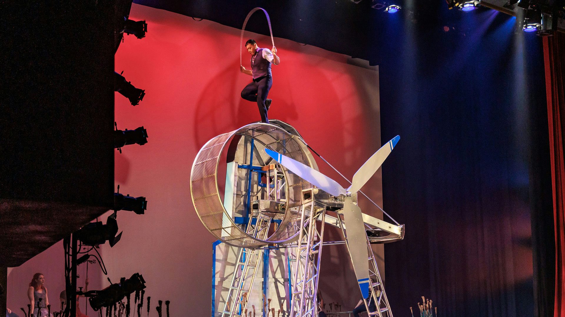 A man jumping rope on a giant moving wheel at a high height.