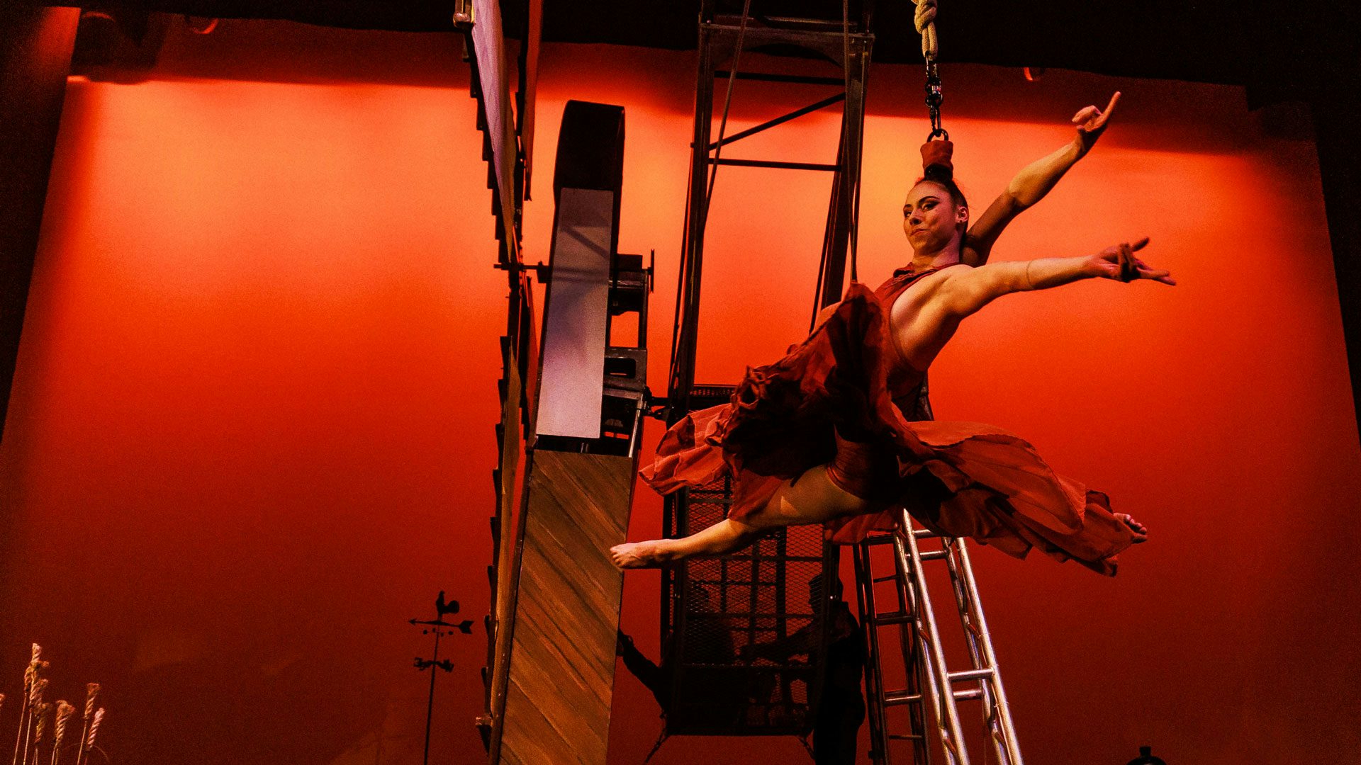 A woman artistically suspends in the air with her hair attached to a rope.