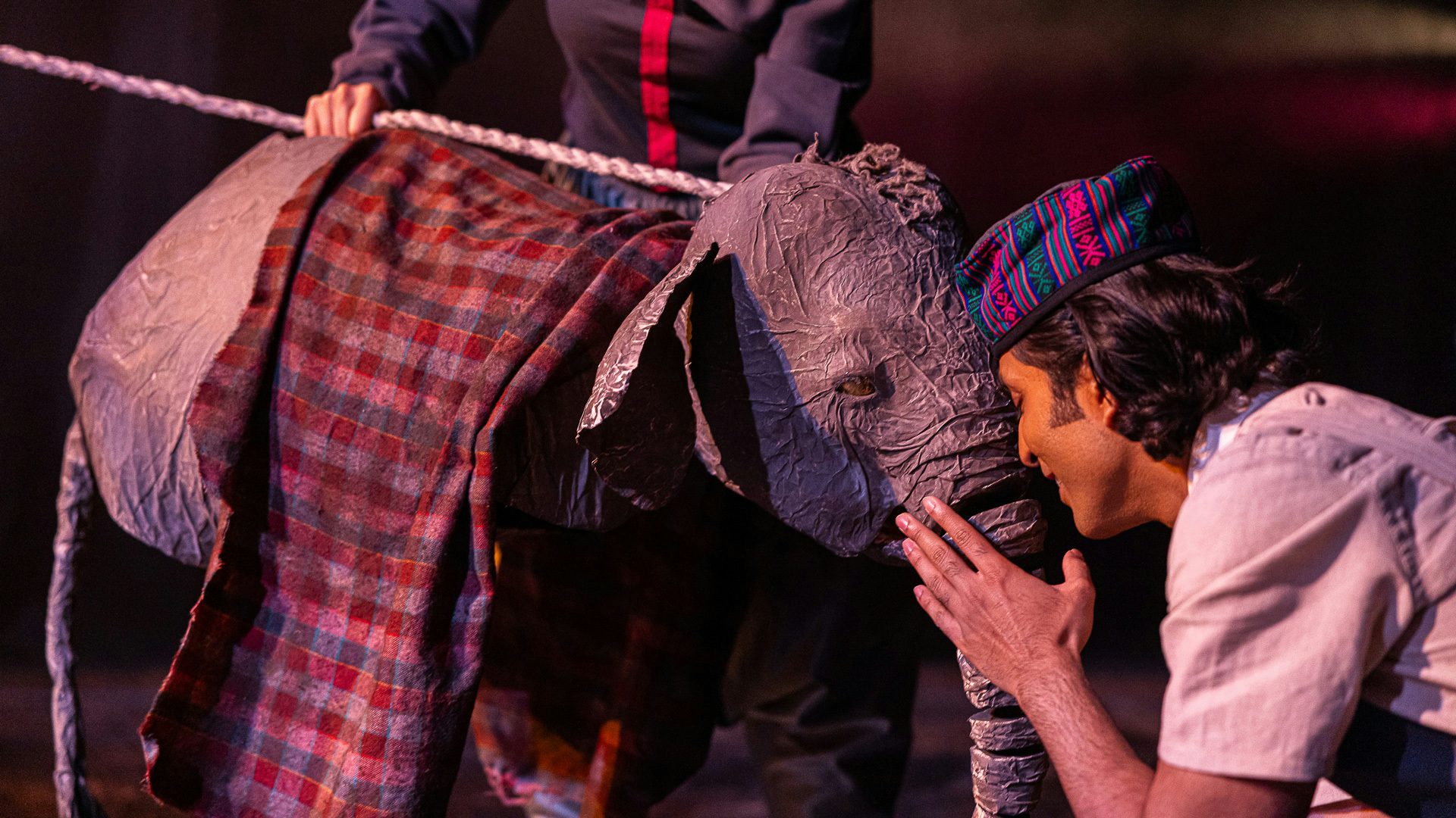 Man in hat forehead to forehead with baby elephant puppet