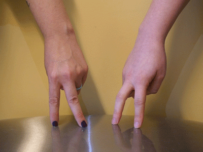 Two sets of fingers kick like legs and drop into splits against a reflective steel surface.