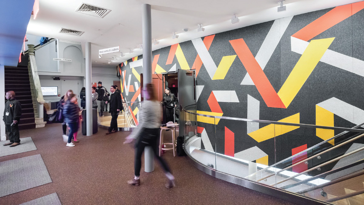 View of the main lobby, with the logo wall and stairs leading down to the cafe and activities
