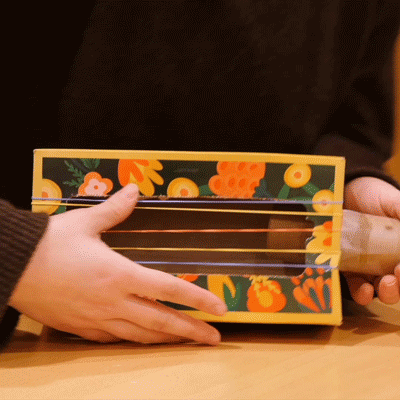 A repeating GIF of the rubber bands in place being strummed by hand.