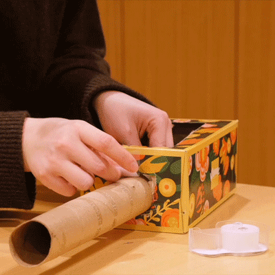 A repeating GIF of the cardboard tube being secured in the hole with tape.