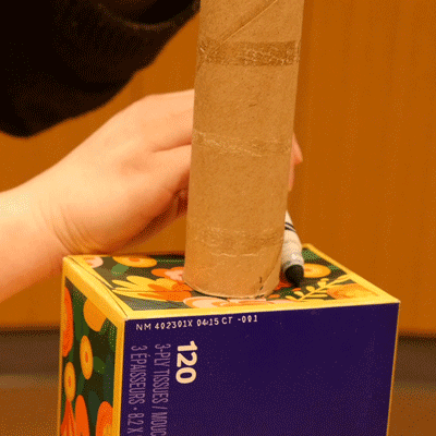 A repeating GIF of a marker tracing the circumference of the cardboard tube against the side of the tissue box.