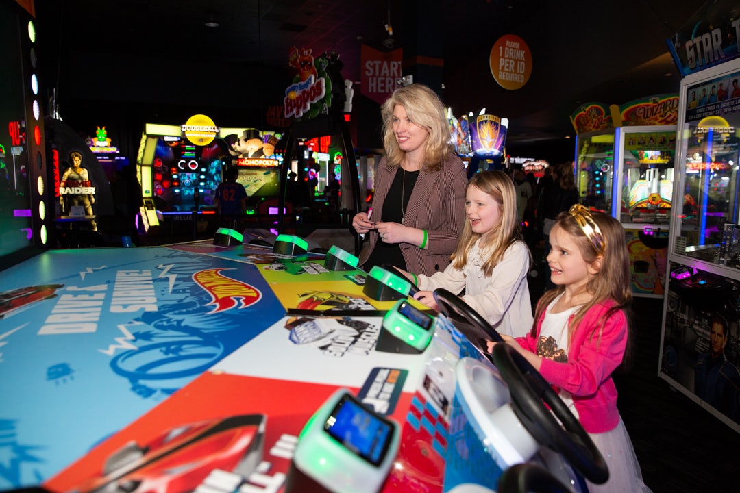 Two kids and an adult play a game in the arcade at Dave & Buster's.