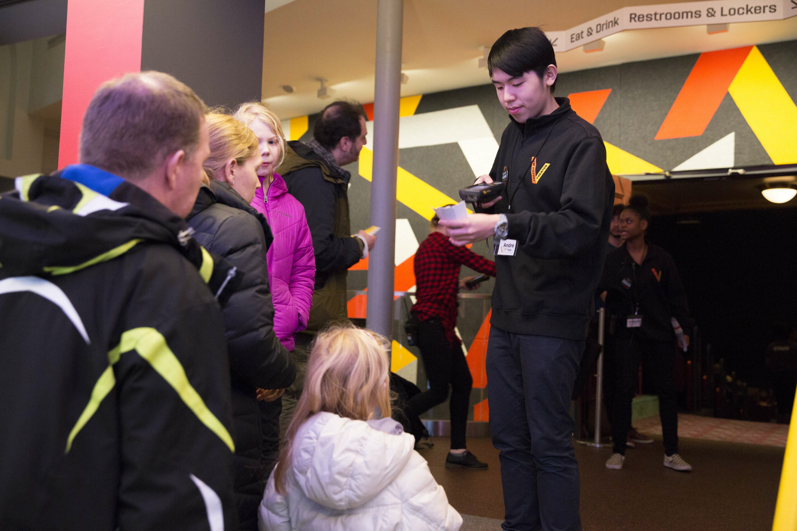 A New Victory usher scanning the tickets of a family entering the theater.