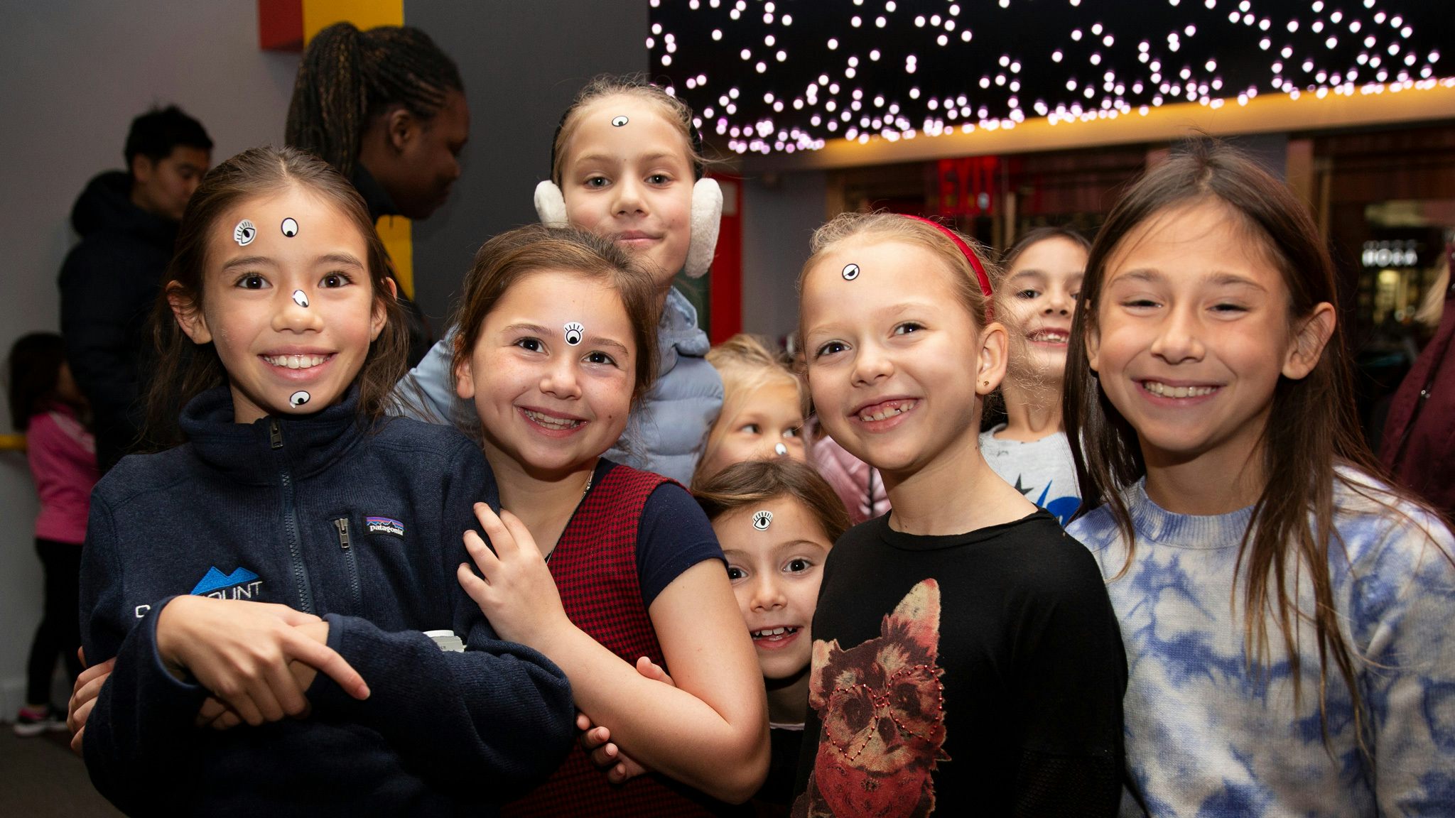 A group of kids smile and have stickers on their faces.