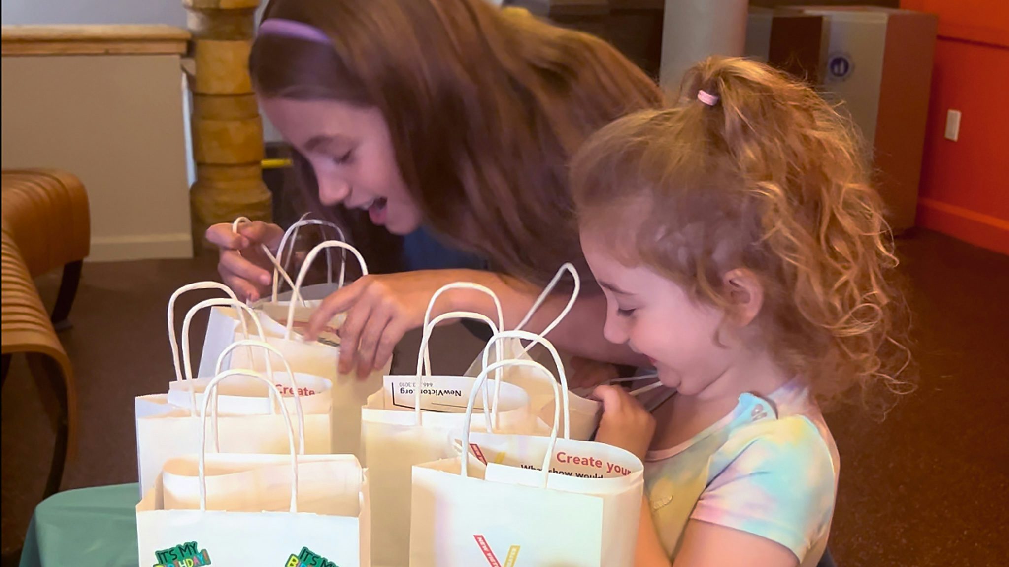 Two kids smile as they look into their goodie bags.