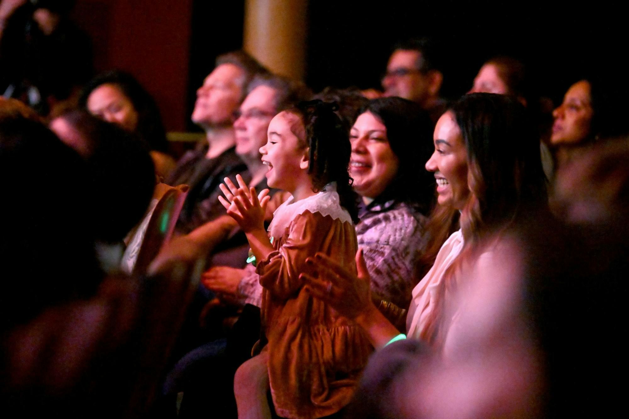 A little girl from the crowd clapping along a show.