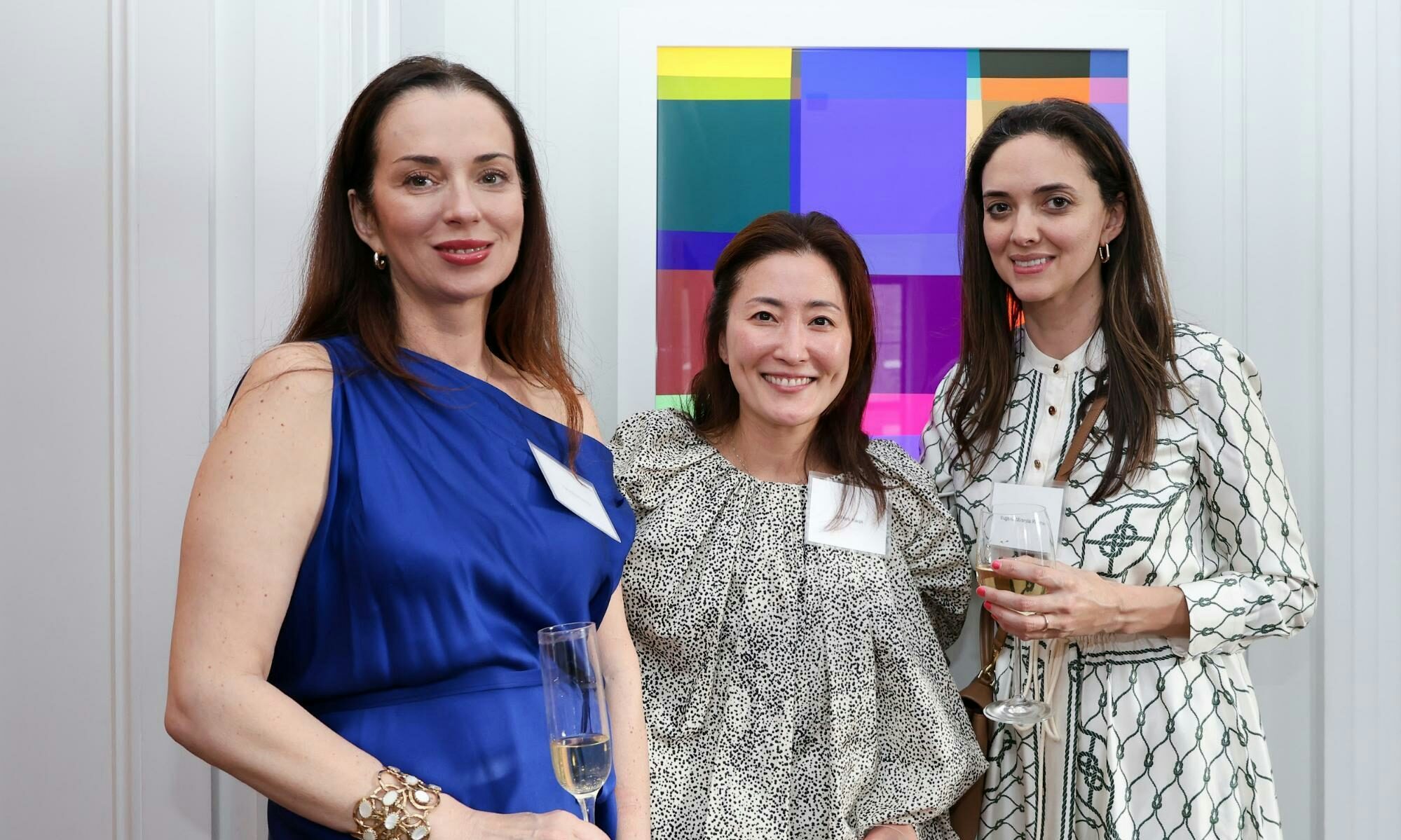 Three women standing in front of colorful art.