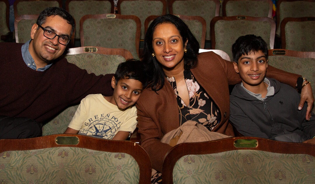 A family sitting in theater seats.