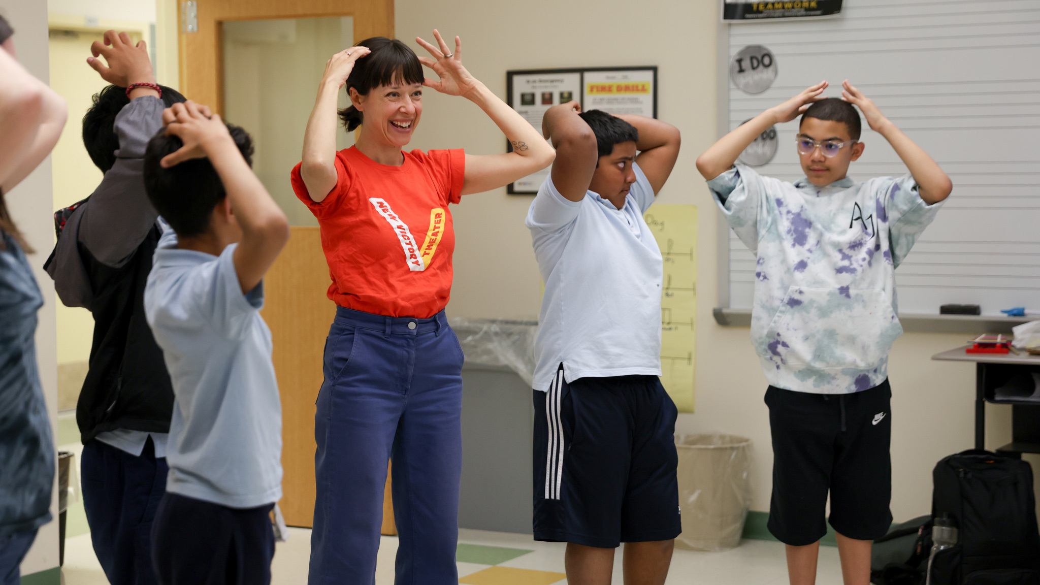 A woman and kids with hands one their heads.