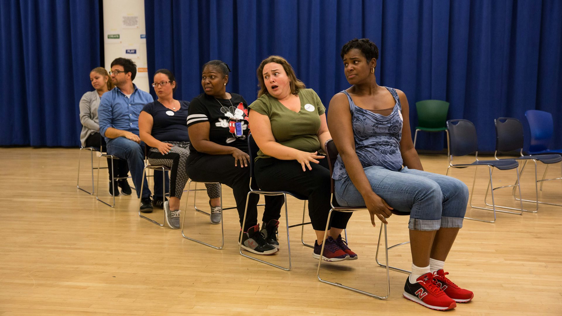 Teachers sitting on chairs in a straight line.