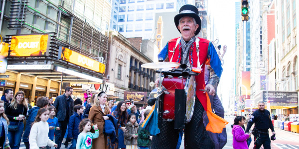 An man hitting a single drum outside.