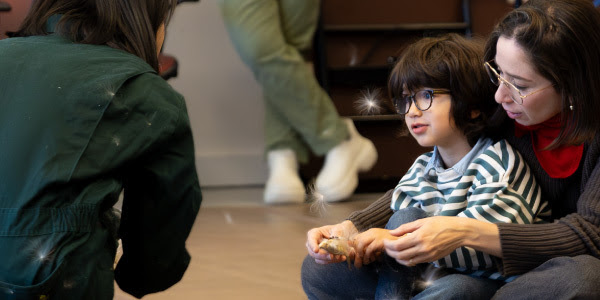 A boy sitting on the lap of a woman wearing a red scarf.